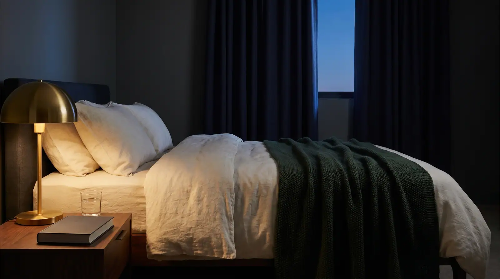 Editorial Schlafzimmer mit Cream-Bettzeug, dunkelgrünem Throw, brass-Lampe — Schlaf-Sanctuary